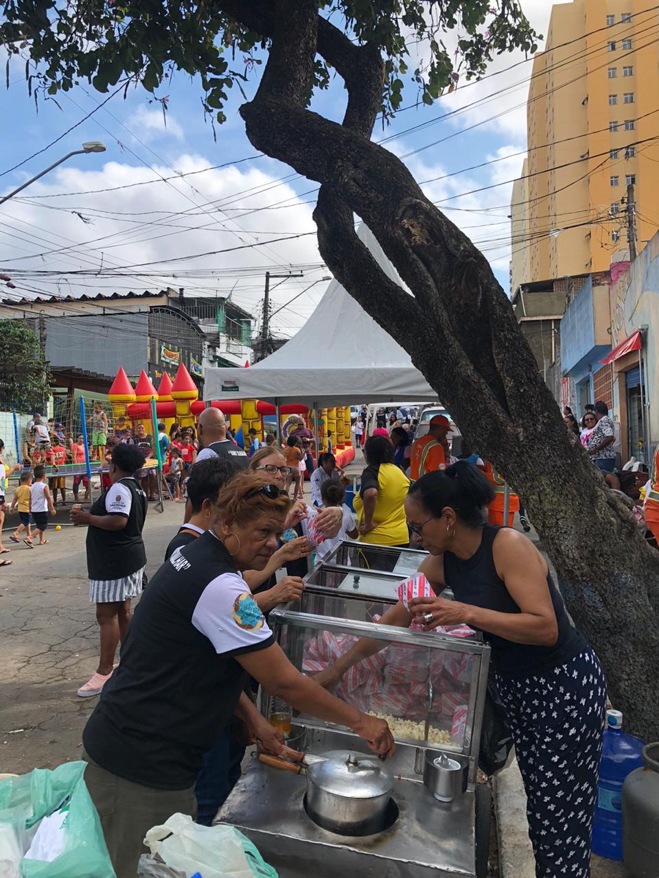 Imagem das mulheres e um carrinho de pipoca elas estão entregando e fazendo pipoca 